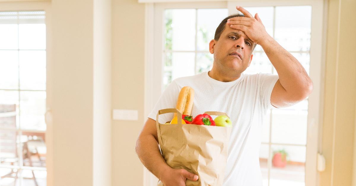 Middle age man holding groceries shopping bag at home stressed 