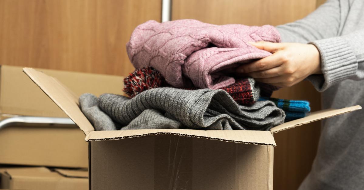 woman in a gray sweater collects clothes in a box
