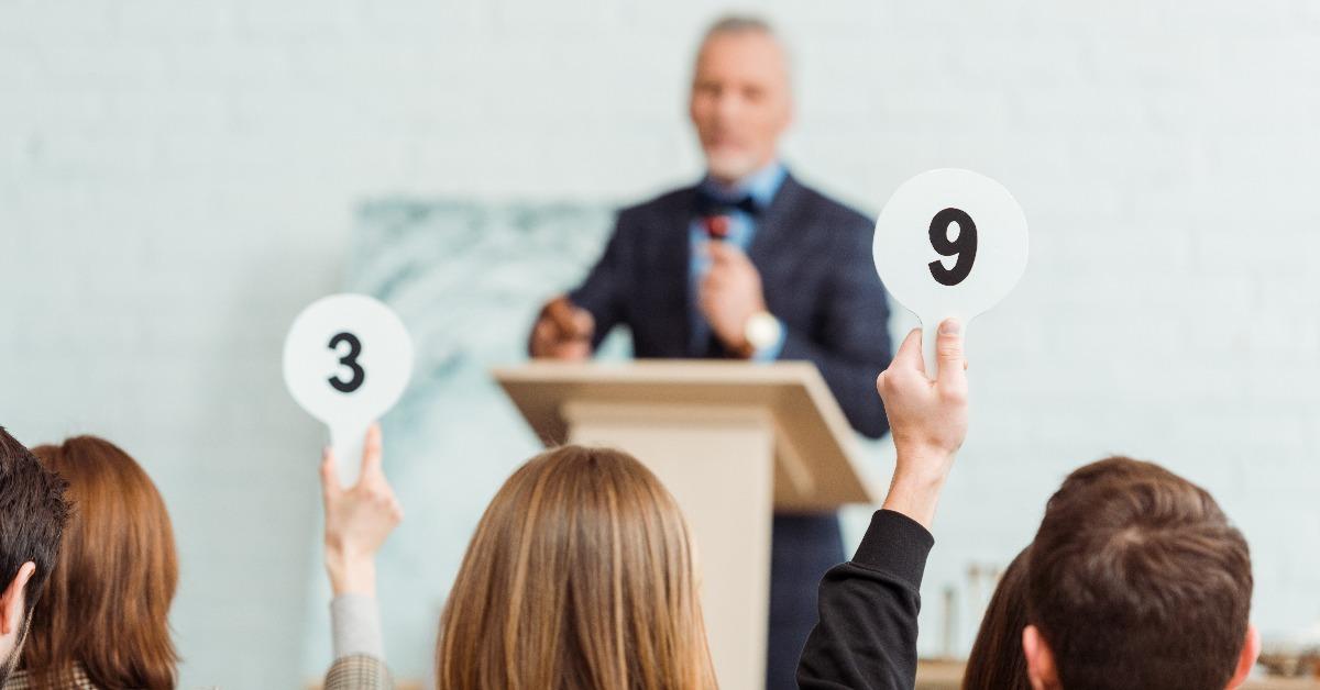 buyers showing auction paddles with numbers nine and three to auctioneer