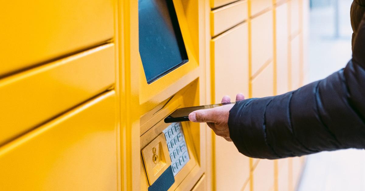 man scanning a code on the mobile phone to pick up a package from the yellow locker