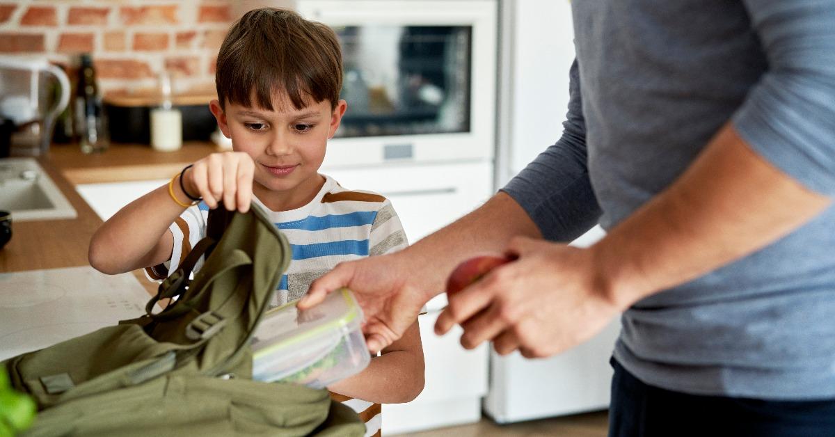 father packing healthy food lunch boxes for son
