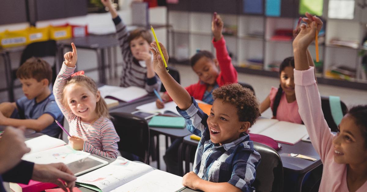 schoolkids raising their hands in classroom