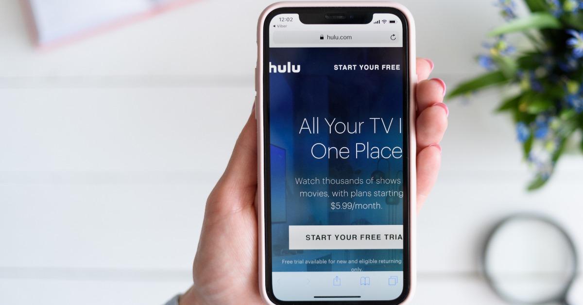 Woman holds Apple iPhone X with hulu.com site on the screen