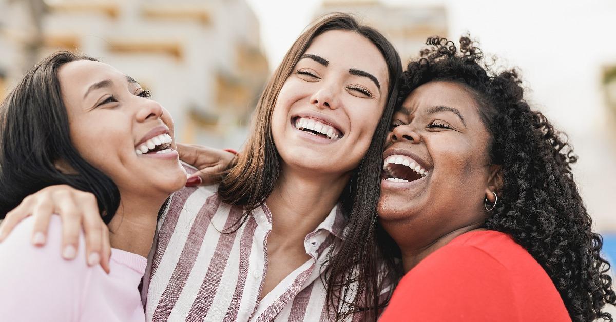  women laughing and hugging each other outdoor in the city