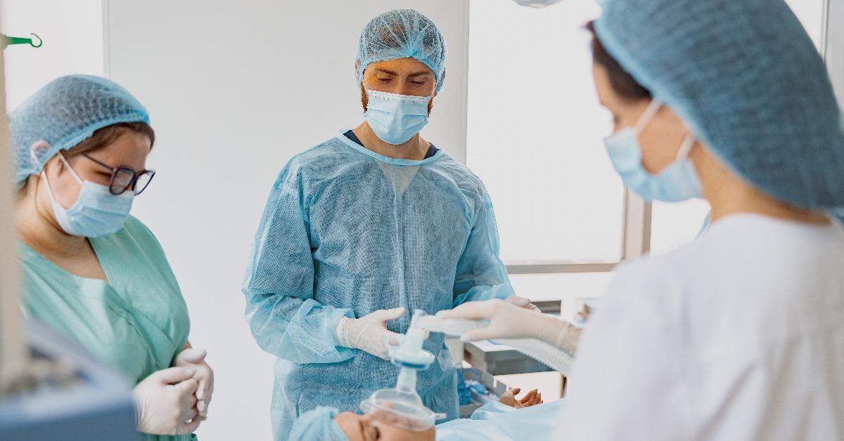 Doctor anesthesiologist holding breathing mask on patient 