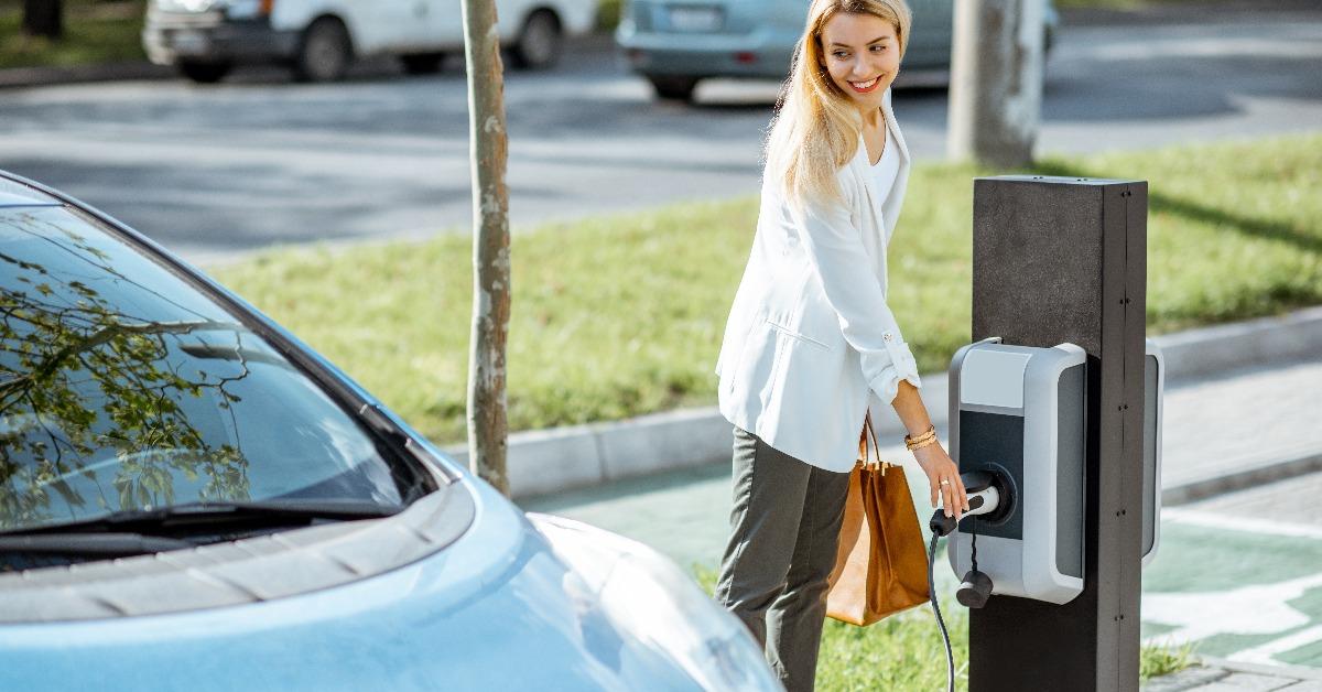 woman plugging charging gun into the electric gas station