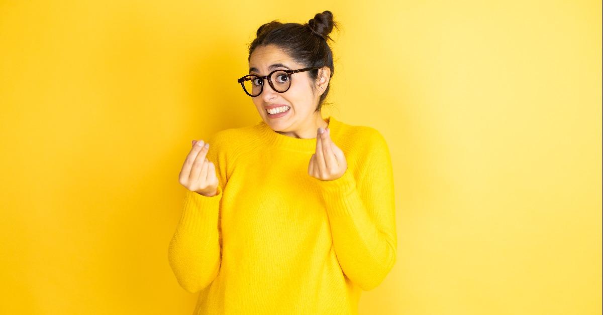 woman wearing casual sweater over isolated yellow background doing money gesture