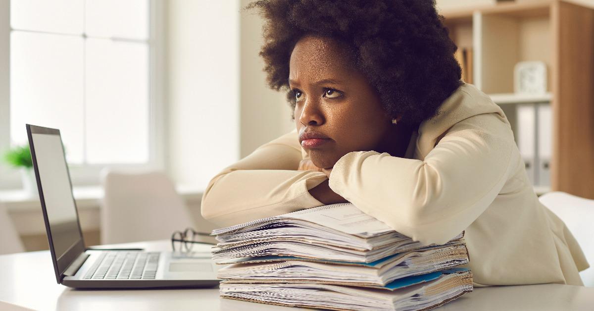 dissatisfied woman employee  sitting at office desk pouting lips with sad face