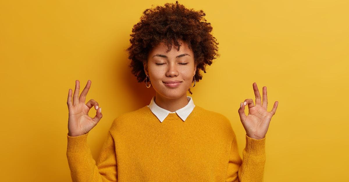 young woman with closed eyes makes yoga gesture