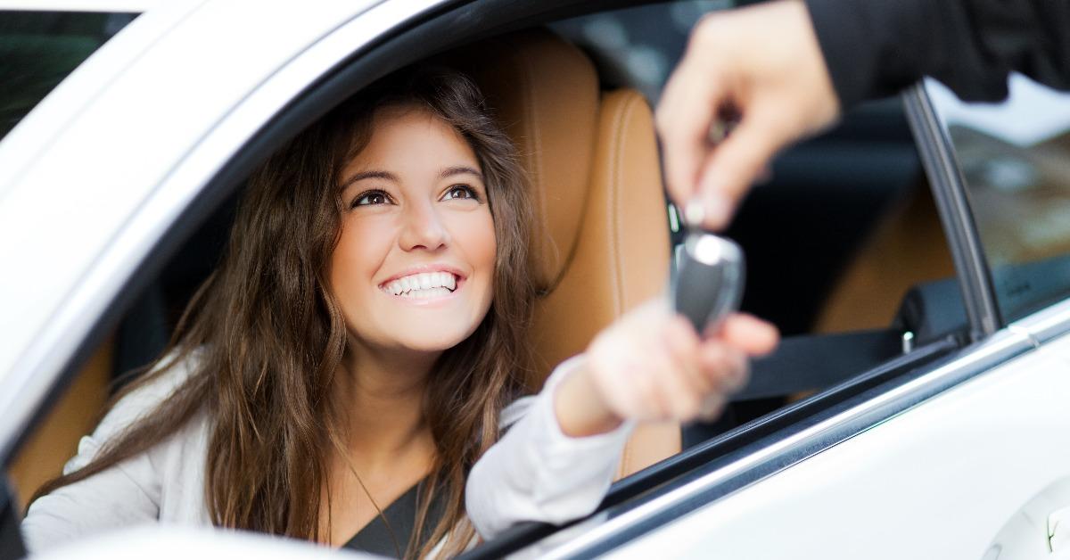 woman receiving keys of her new car from dealer