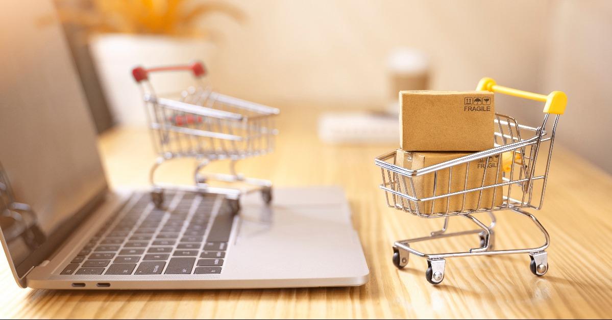 brown paper boxes in a shopping cart with laptop keyboard on wood table