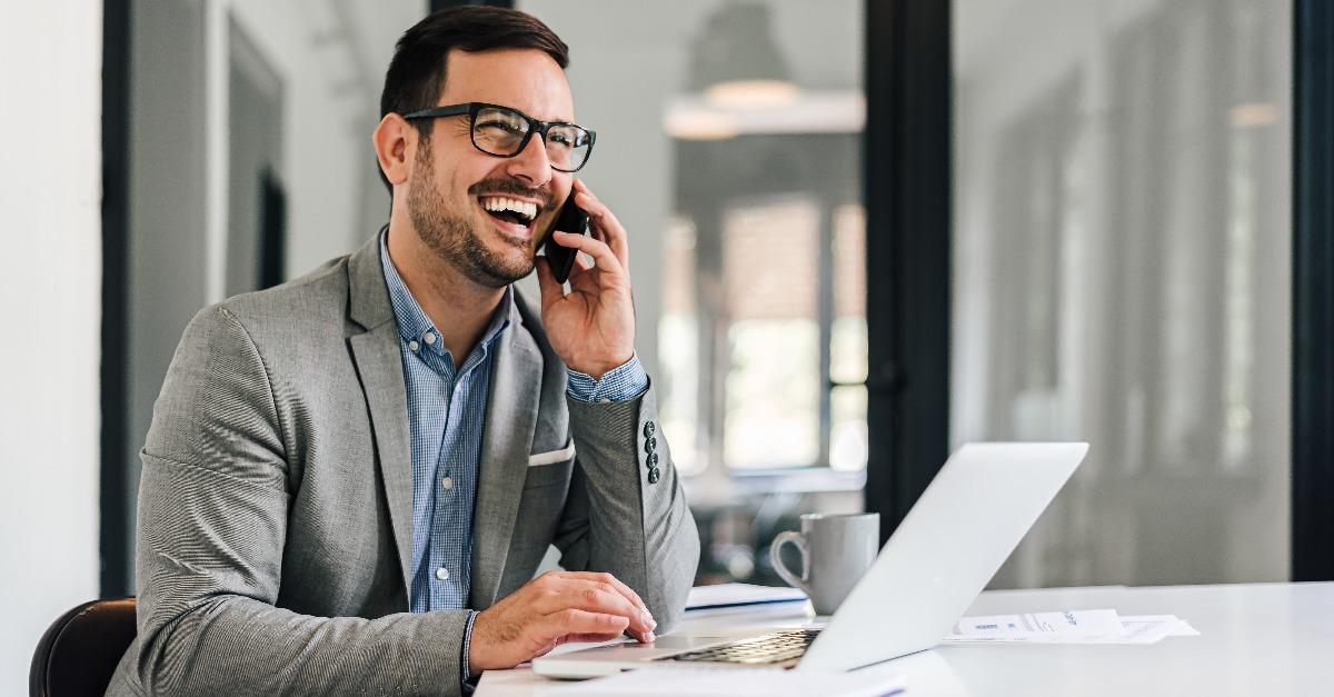 happy entrepreneur talking on mobile phone while using laptop