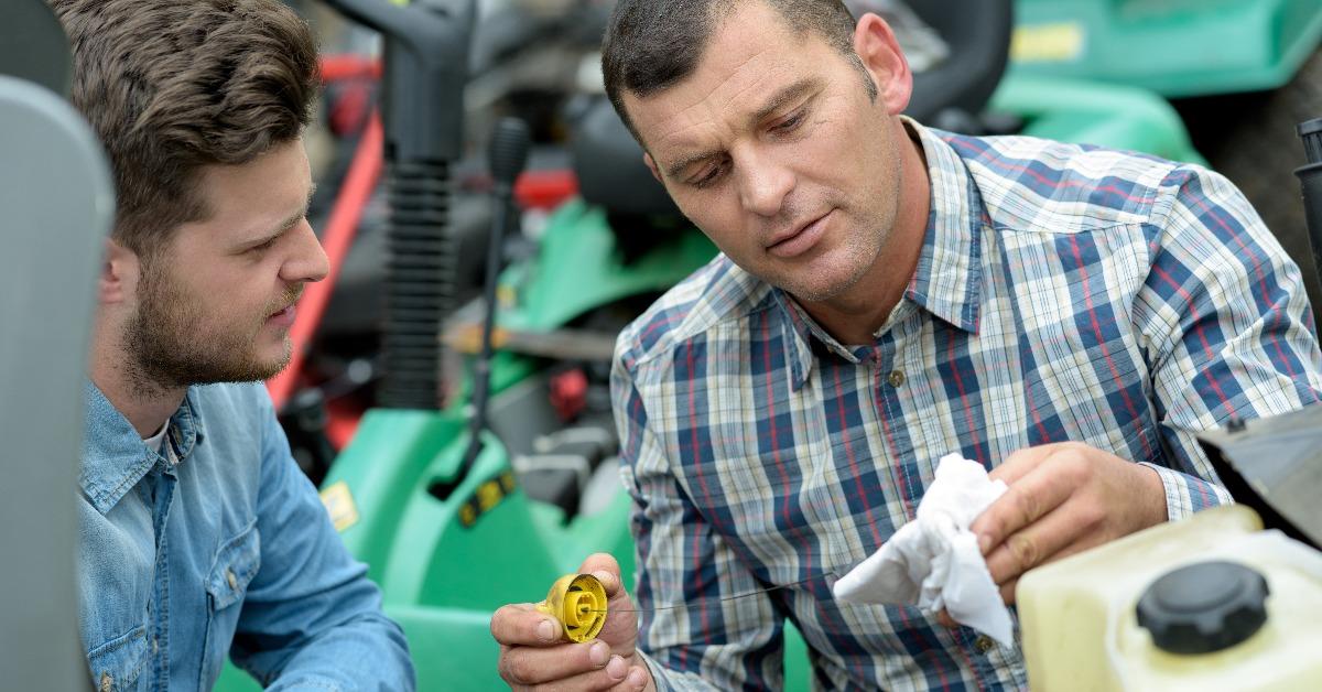 portrait of men repairing lawn mower engine