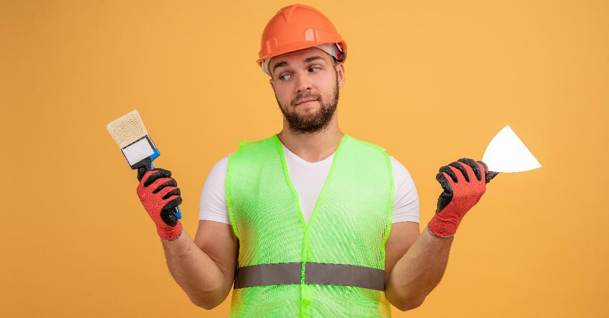 puzzled painter man holds paint brush and spatula