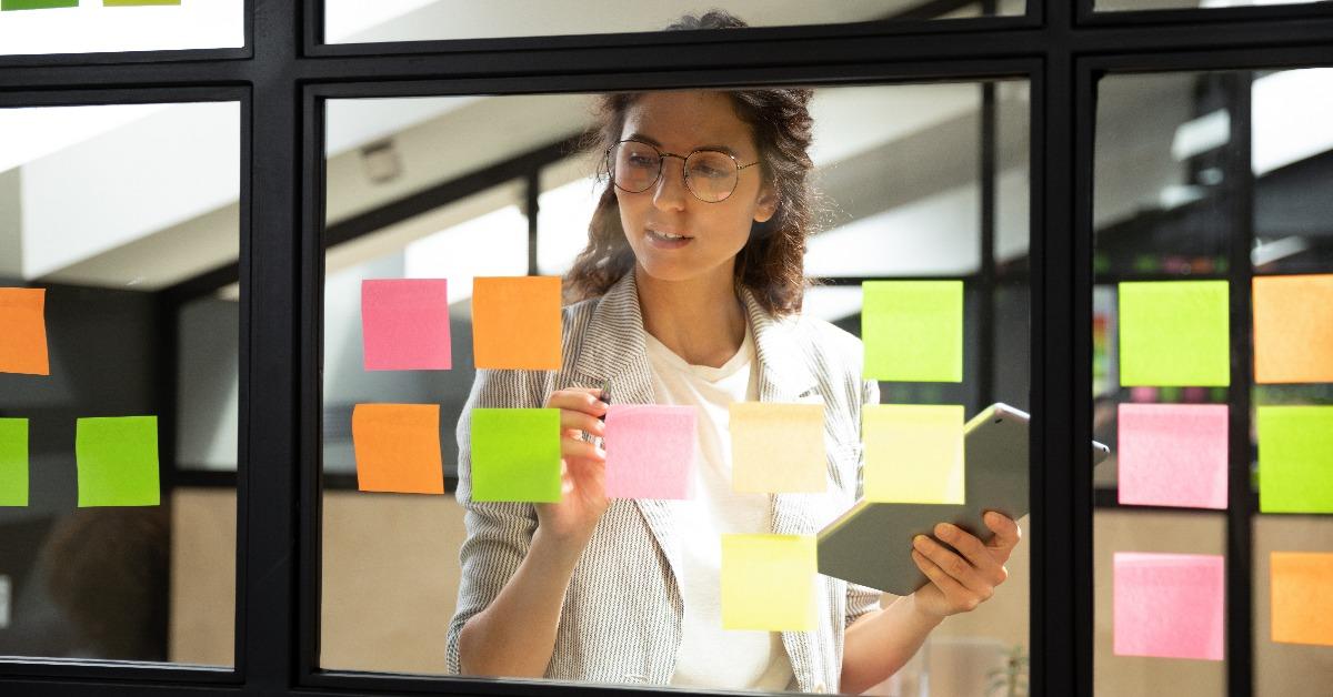businesswoman creates priority to-do list on sticky notes