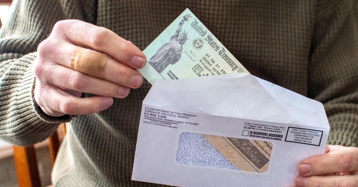 man's hand holding an economic aid check 