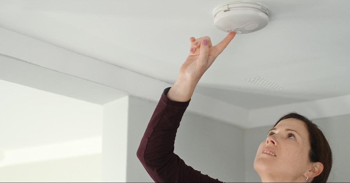 young adult woman checking fire alarm