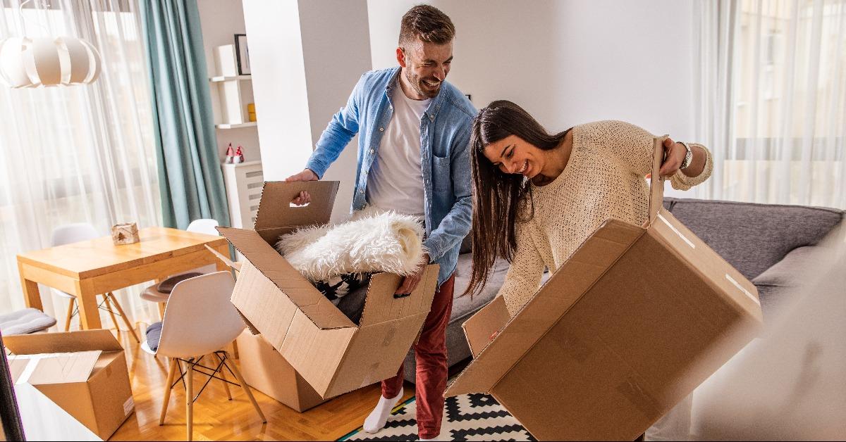 young couple move into a new home carrying boxes of belongings