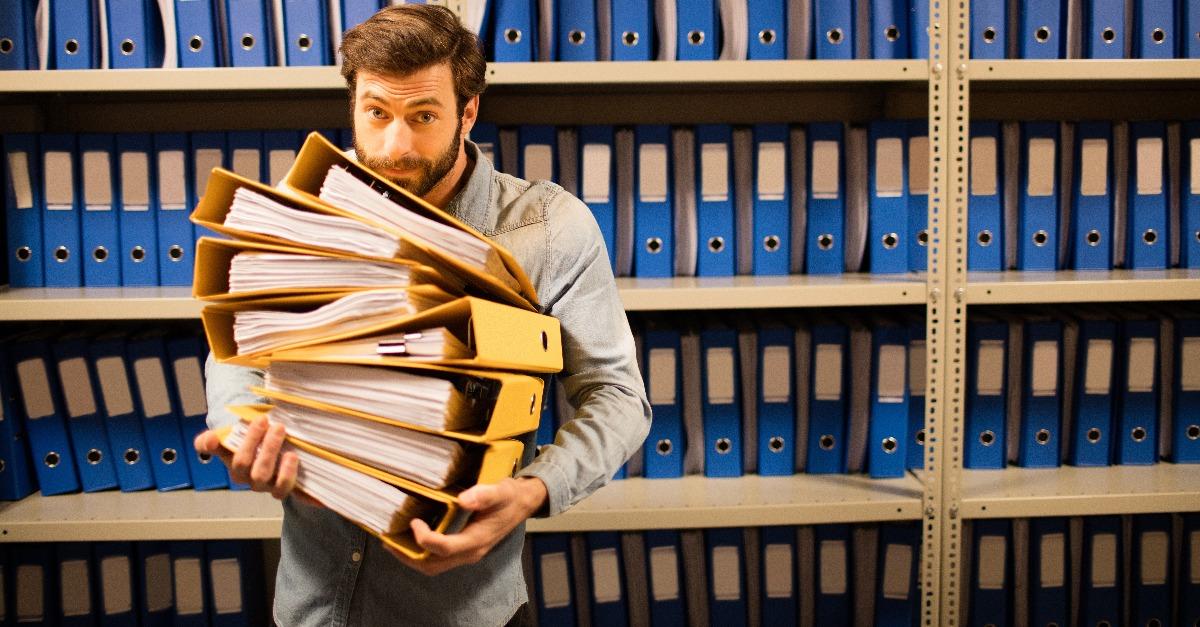 businessman holding stack of files in storage room