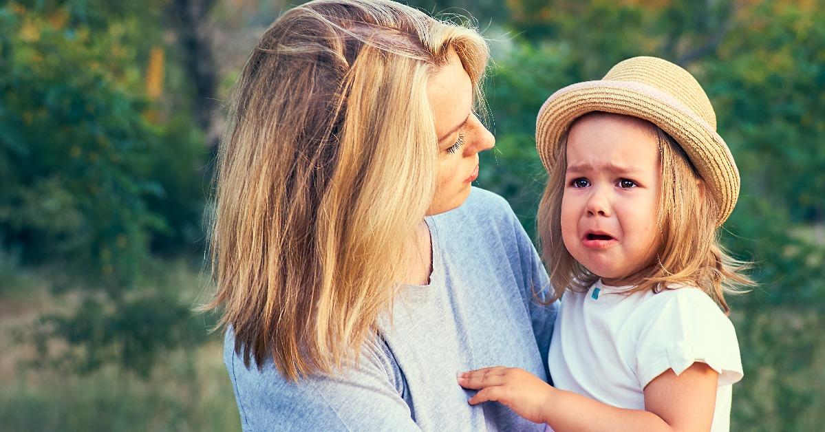 mother comforts her crying little girl outdoors 