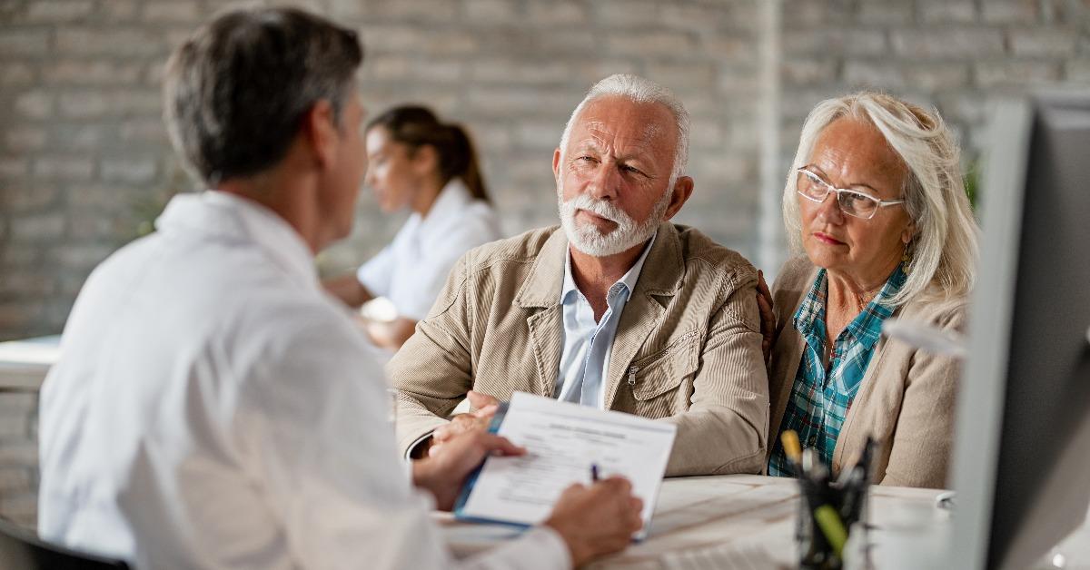 mature couple planning their health insurance policy with a doctor at clinic