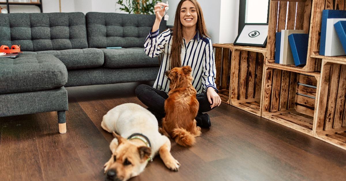 woman holding key of new house sitting on floor with dogs