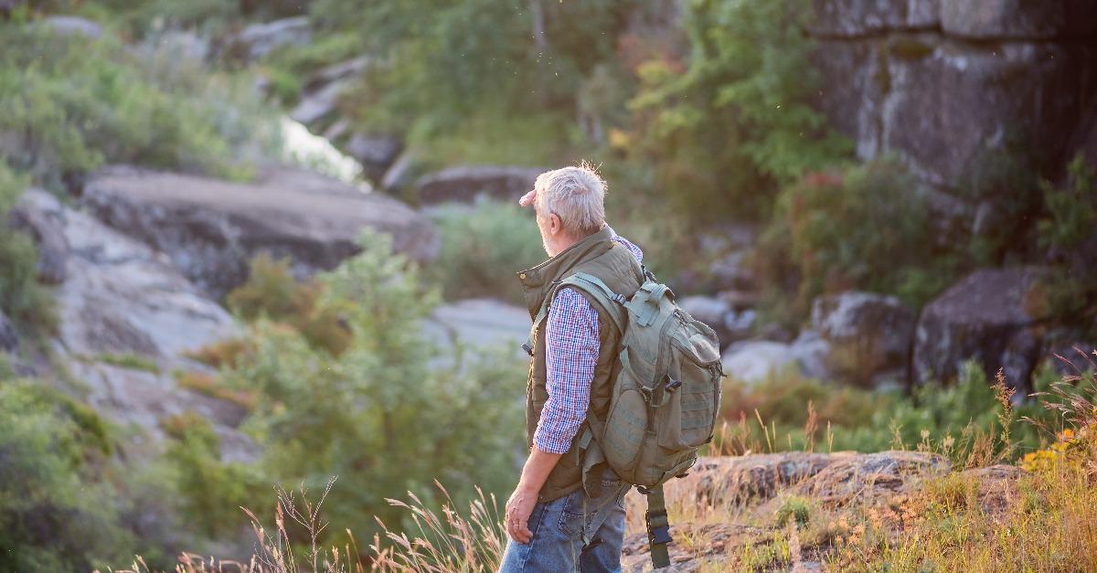 tourist man with a gray beard with a backpack on his shoulders 