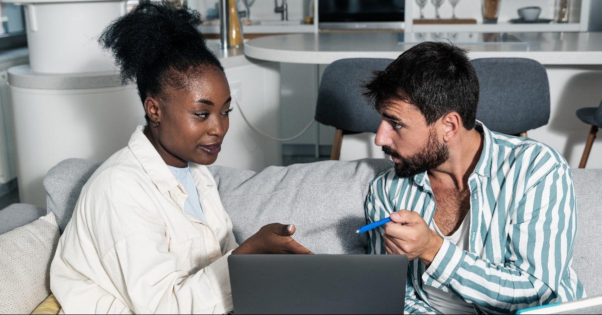 mixed race couple sitting on the sofa in their home calculating taxes