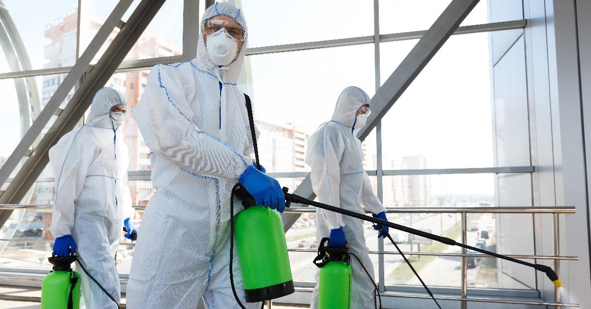 workers in hazmat suits disinfecting indoor accommodation