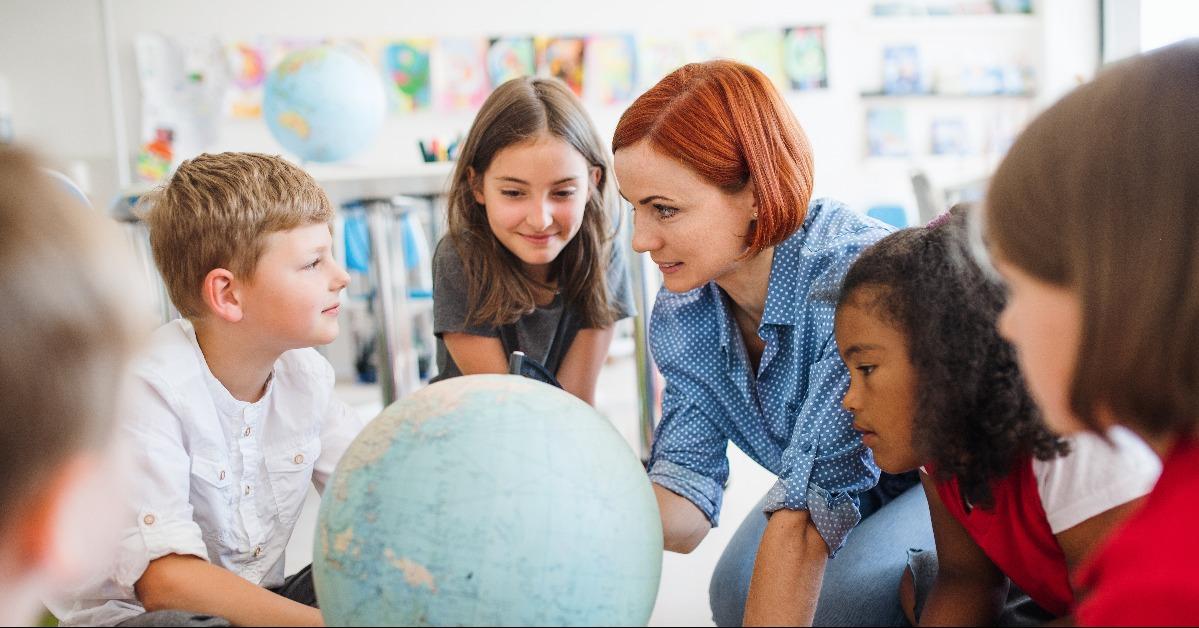 small school kids with teacher sitting on the floor in class