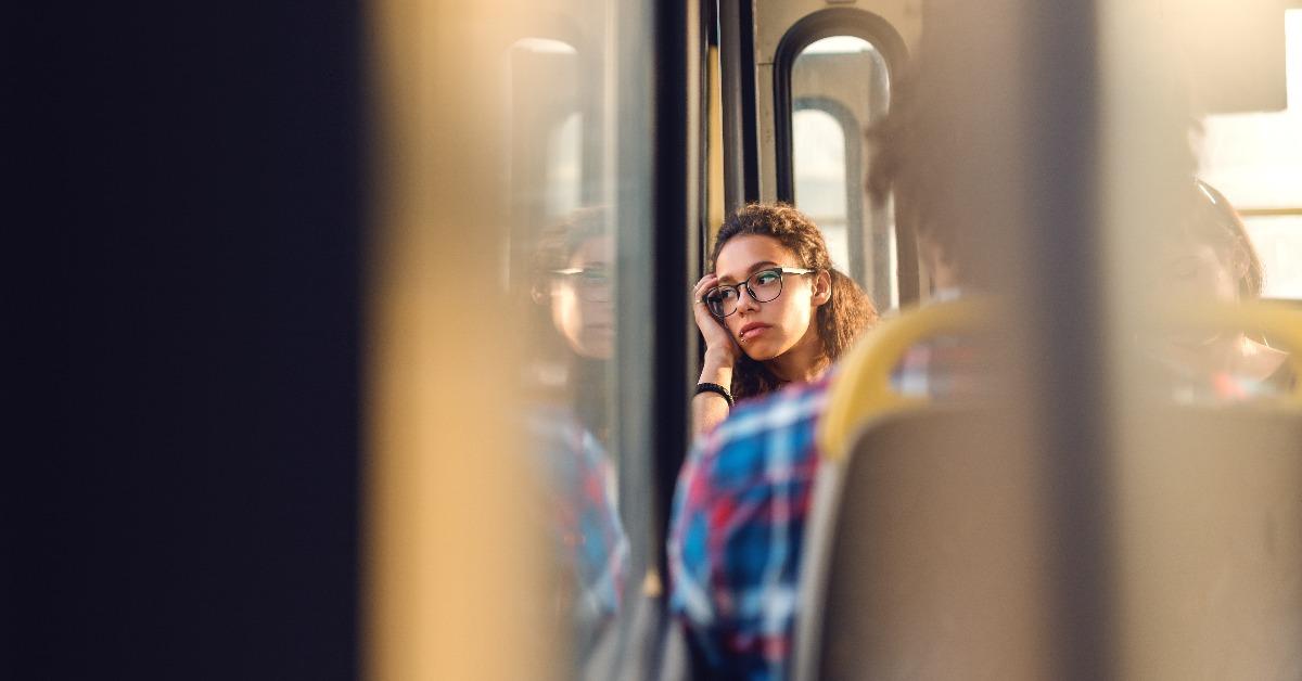 girl looking through window while sitting in public transportation