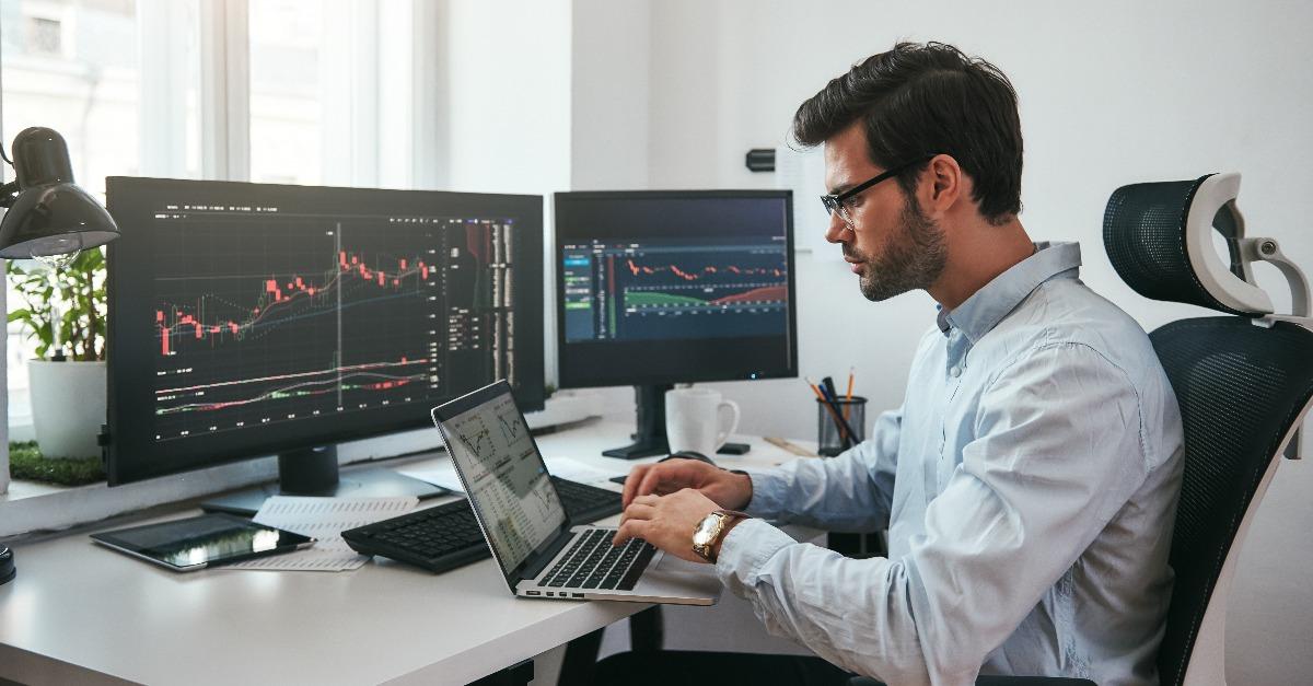 trader wearing eyeglasses using his laptop while sitting in office