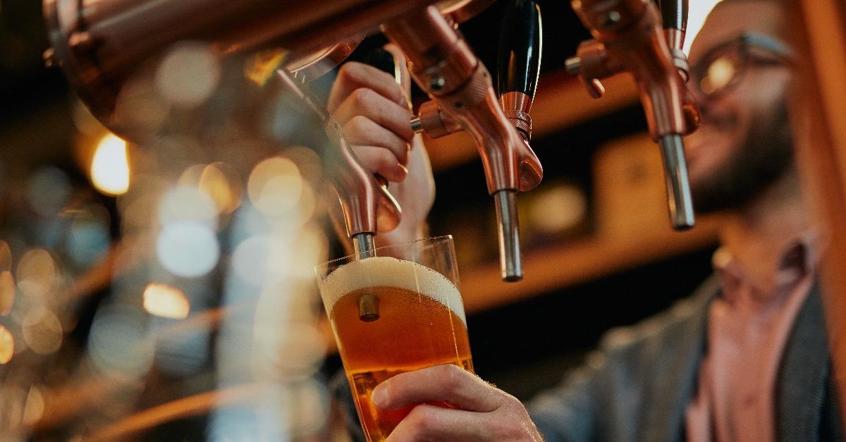 barman pouring beer while standing in pub