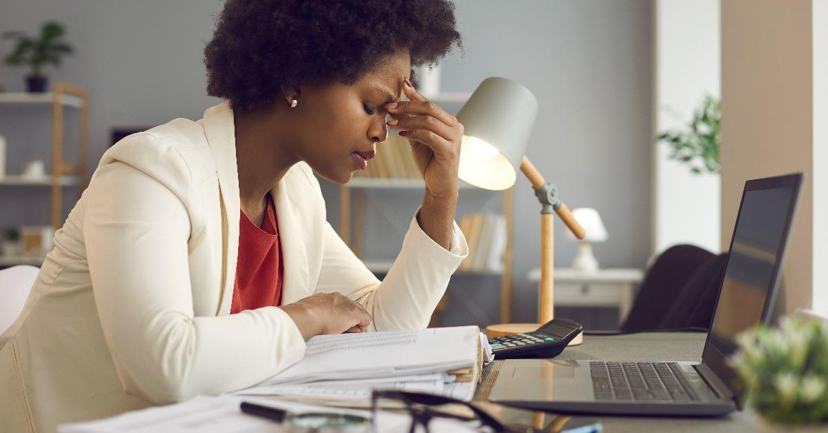 woman keeping eyes closed and massaging nose after working at laptop for long time