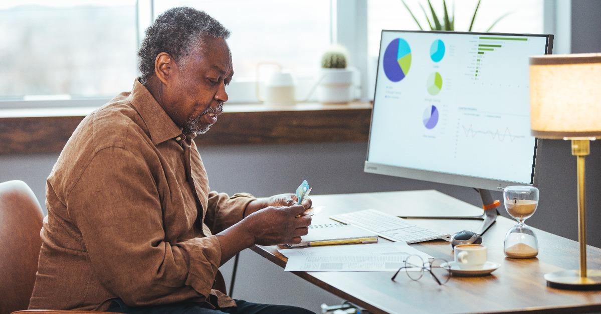 man having a headache while paying bills online at home