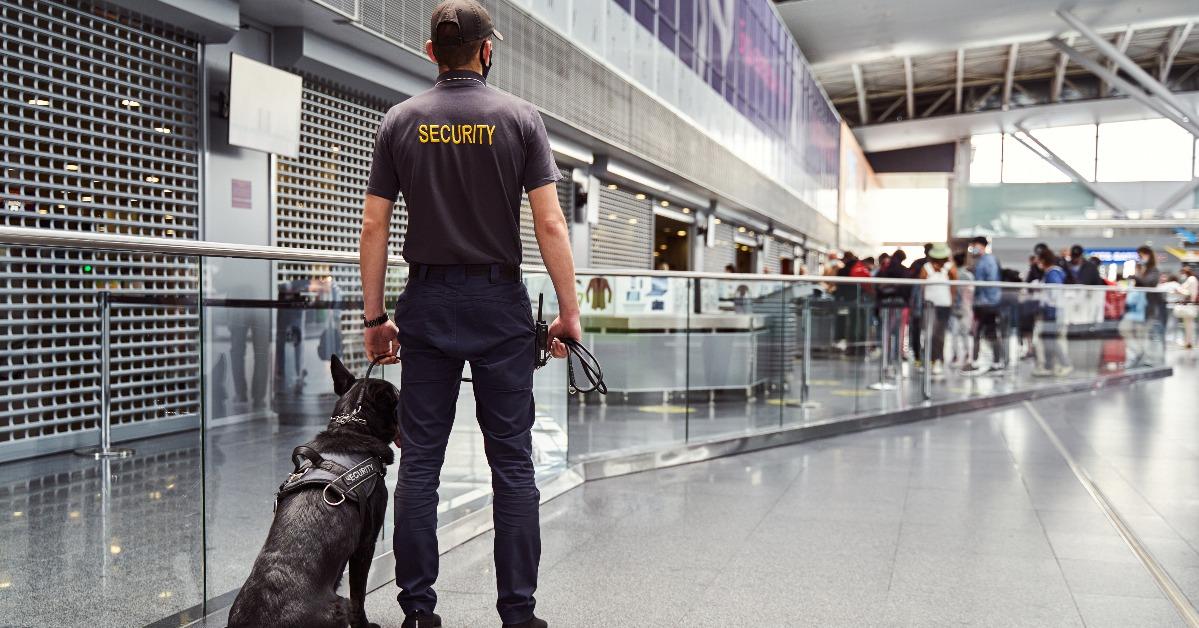 security worker with detection dog patrolling airport terminal