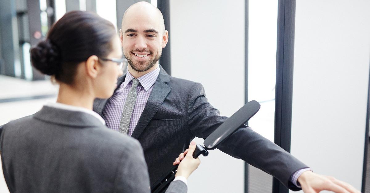 smiling businessman looking at young airport security scanning his arm by entrance