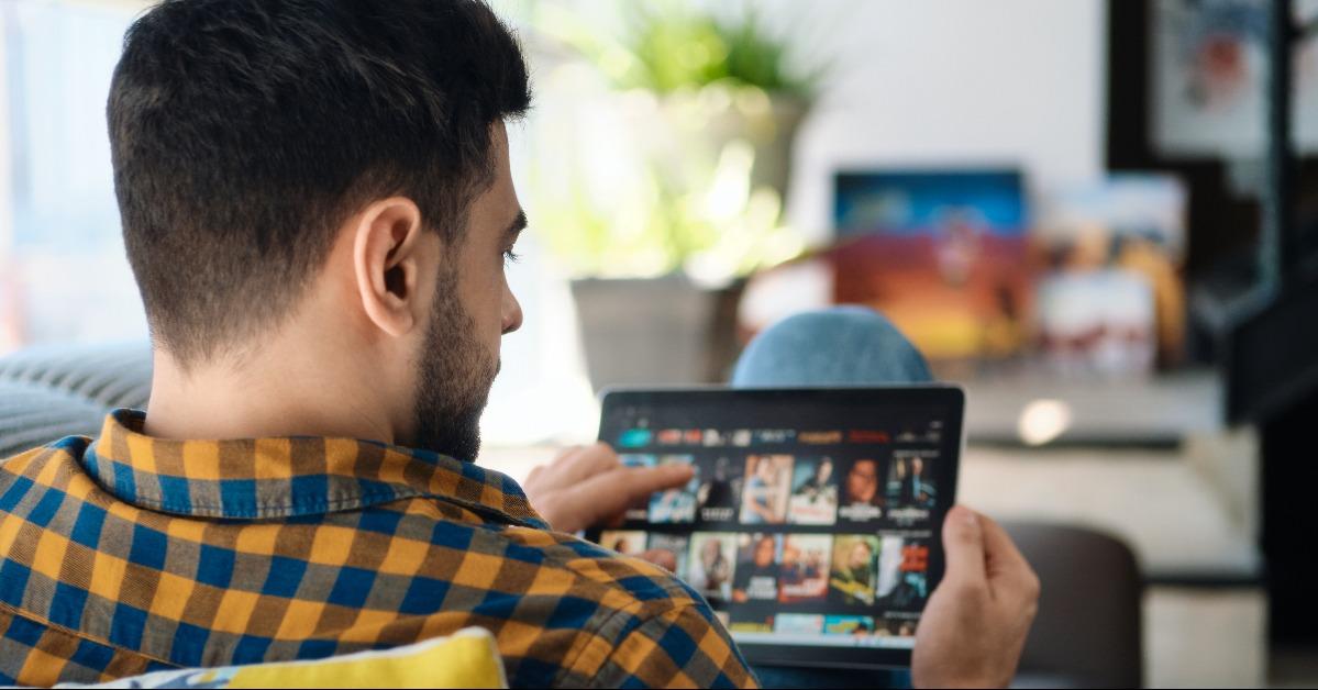 man choosing movie for streaming on tablet computer