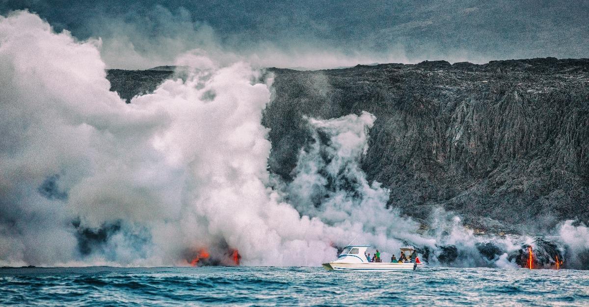 tourists watching the lava reaching the water with toxic fumes