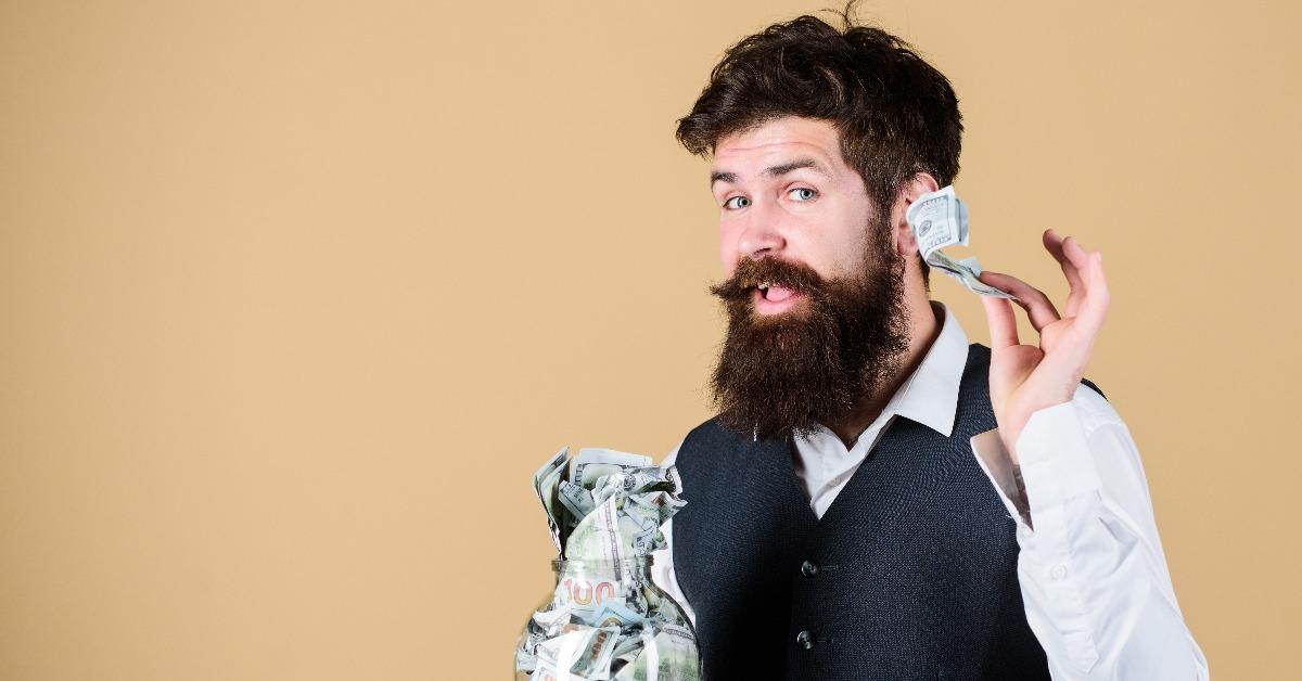 bearded guy hold jar full of cash savings
