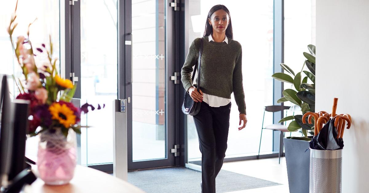 businesswoman arriving for work at office walking through door