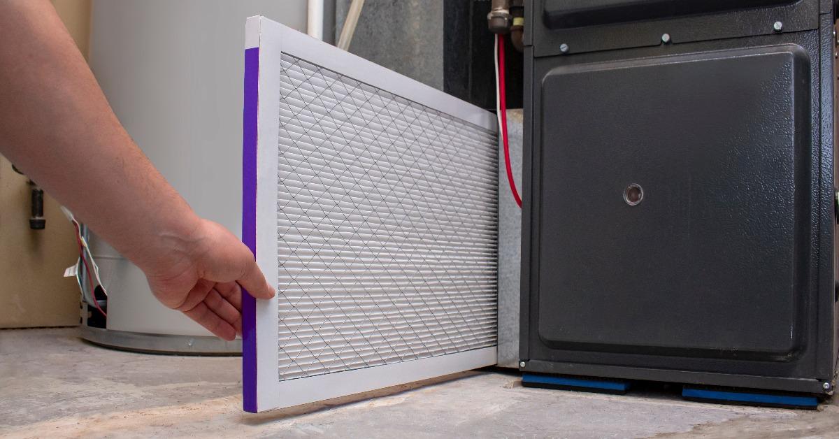 person changing an clean air filter on a high efficiency furnace