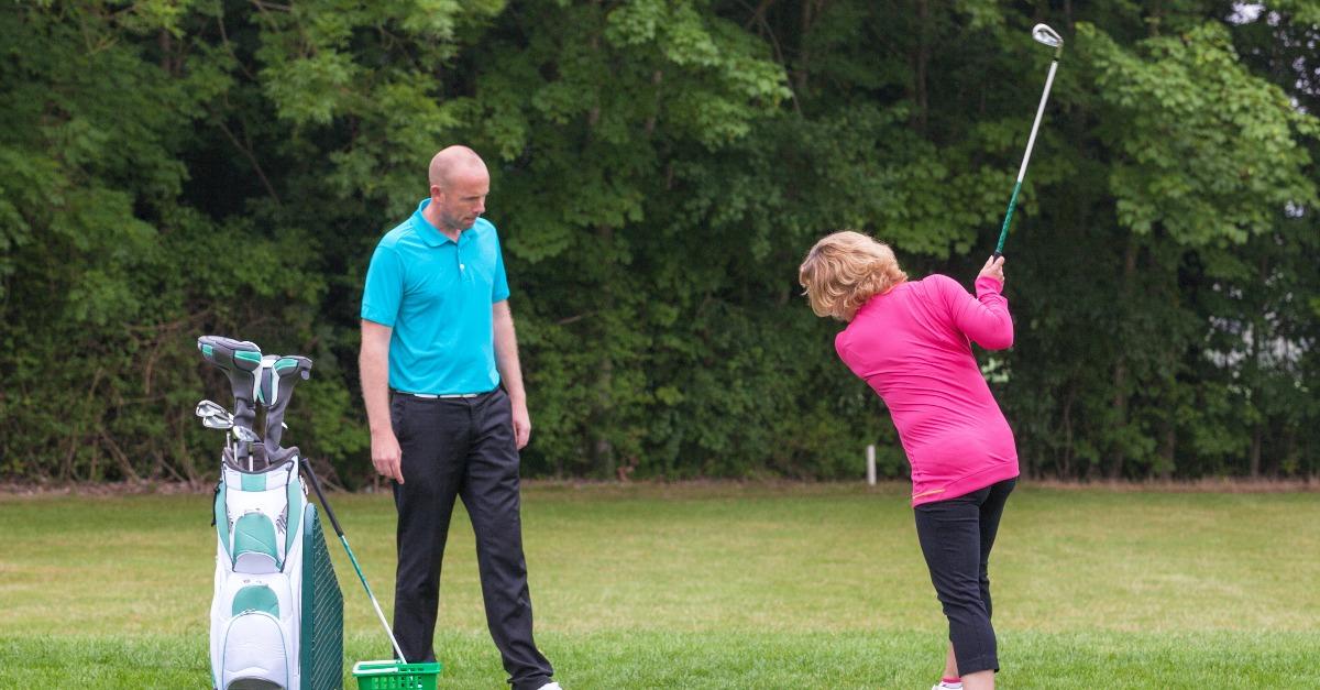 golf pro assessing a lady golfer backswings