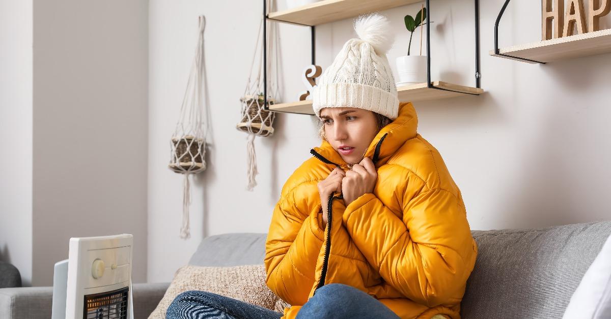  woman sitting near electric heater at home