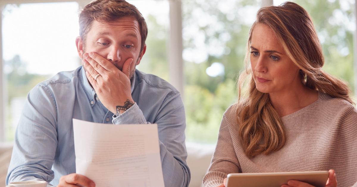 worried couple with bills and digital tablet
