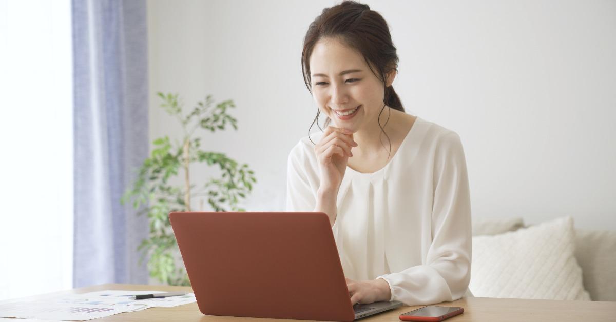 young woman smiling in front of a laptop