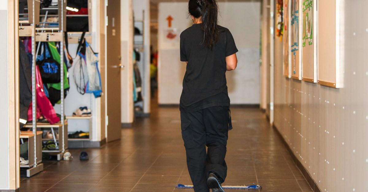 a young female sweeping school corridor