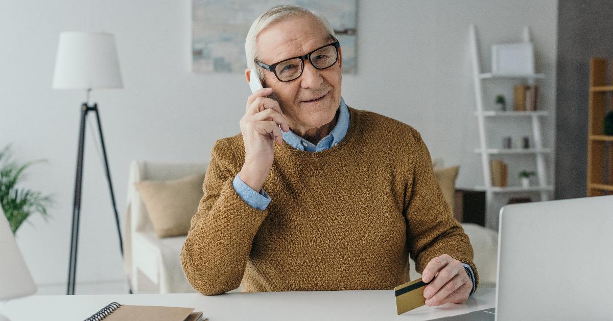 elder smiling man working in office and making phone call