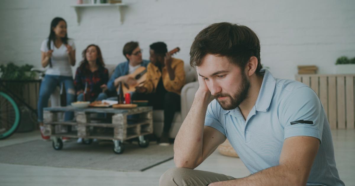 guy feels upset and isolated while his friends are celebrating party at home
