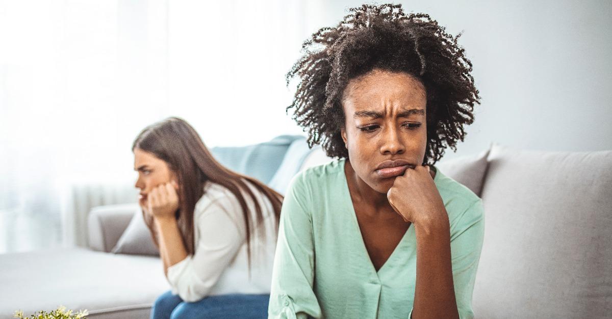 two female friends sitting on sofa and arguing with each other